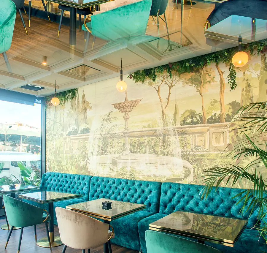 Le lounge de KANTI : banquettes en velours turquoise capitonné et fresque de jardin peinte à la main