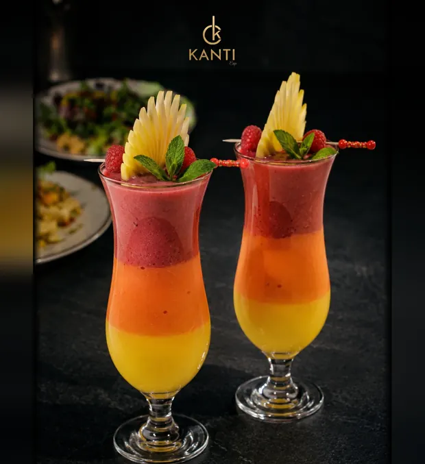 Deux smoothies Exotique étagés — fraise, mangue et orange — sous le monogramme KANTI